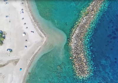 Η άγνωστη παραλία 2 ώρες από την Αθήνα με τον κυματοθράστη «μπανάνα», που τη μετέτρεψε σε παράδεισο